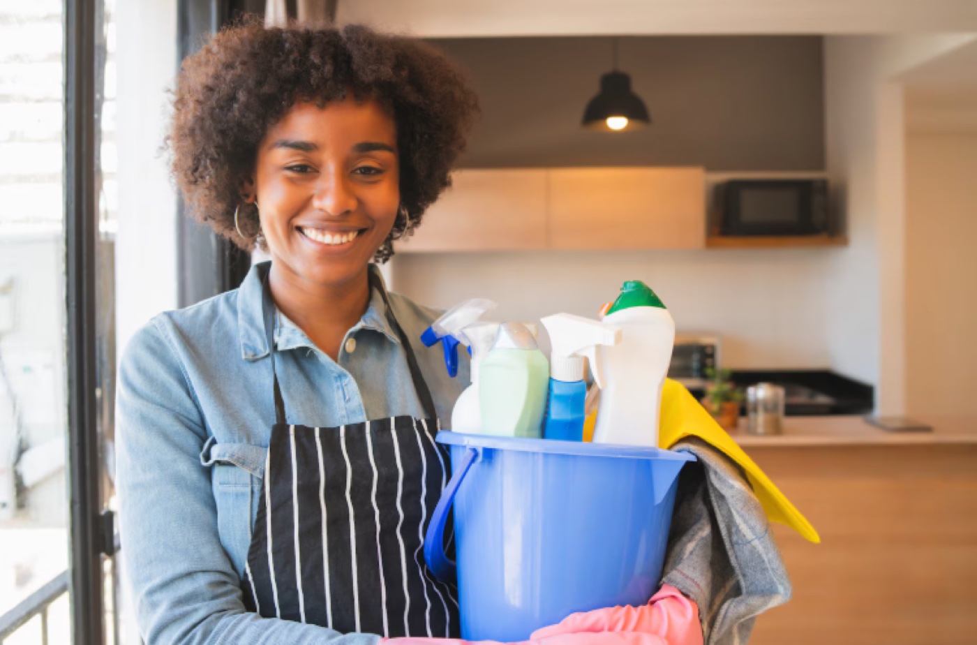 Domestic worker smiling with cleaning supplies